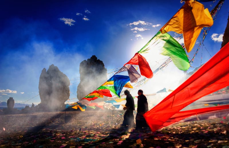 Tibeter vor Gebetsfahnen in Steppe