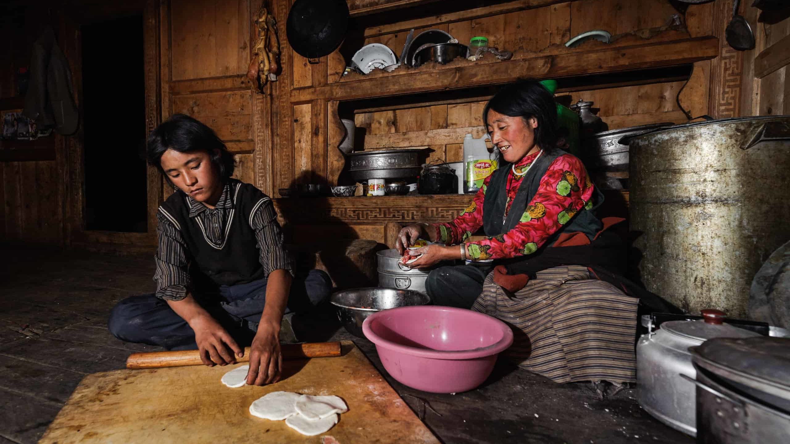 A Tibetan mother and son preparing momos (Tibetan dumplings) at home. Remote village in Tibetan plateau
